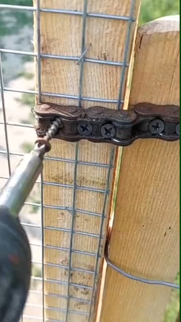 This may contain: a close up of a chain attached to a wooden fence with a drill in the foreground