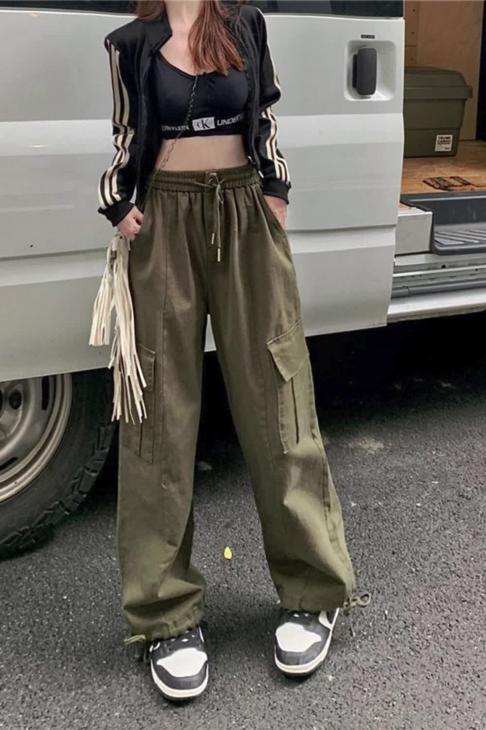 This contains: Introducing the ultimate Women Cargo Pants, designed to combine fashion with functionality. Uniquely crafted for streetwear, these pants feature multiple pockets and an elastic high waist for comfort and versatility. Get ready to elevate your casual wardrobe with these loose, wide-leg trousers.