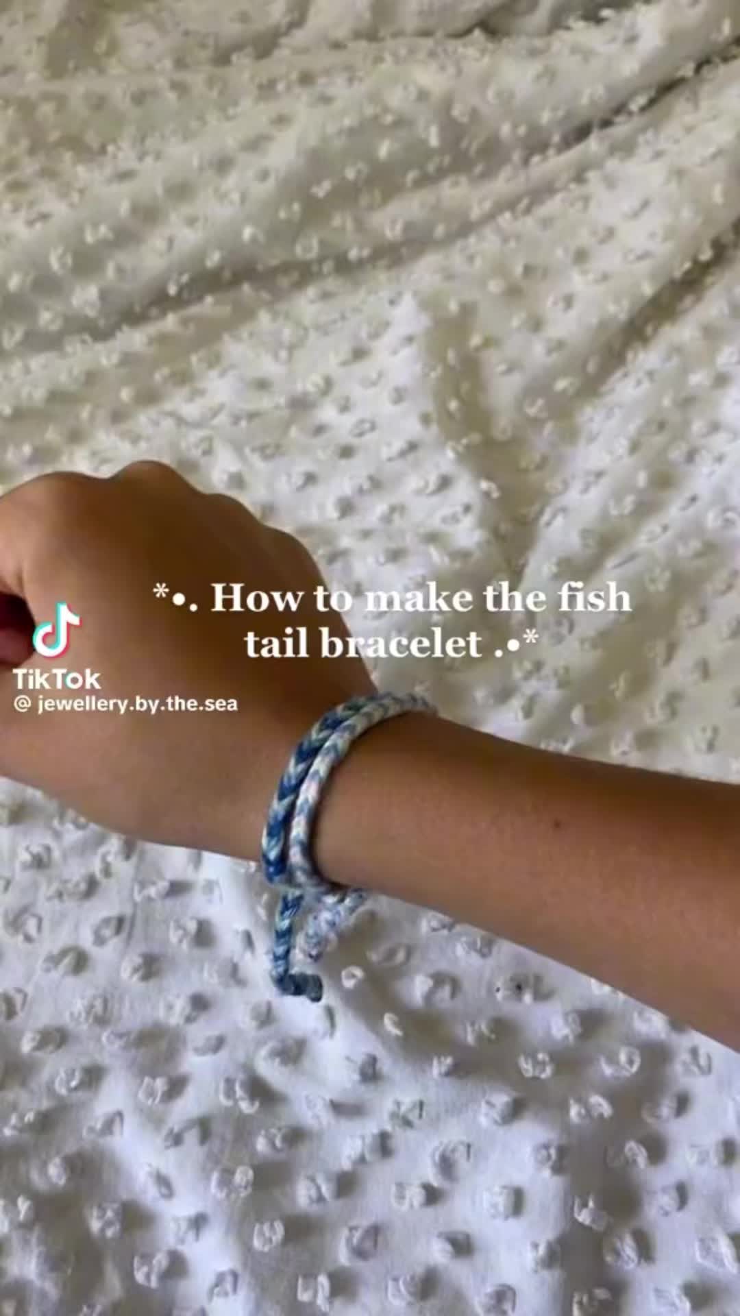 This may contain: a person is holding an object in their hand with the words how to make the fish tail bracelet