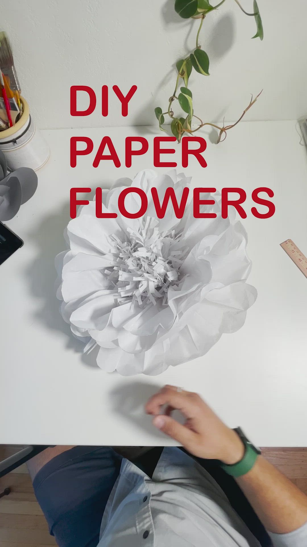 This may contain: a hand holding a large white flower with the words diy paper flowers on it