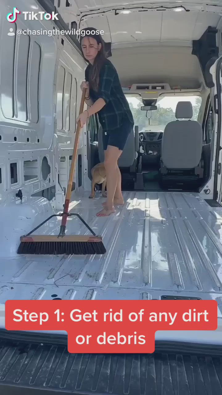 This may contain: a woman cleaning the inside of a van with a broom and duster in her hand