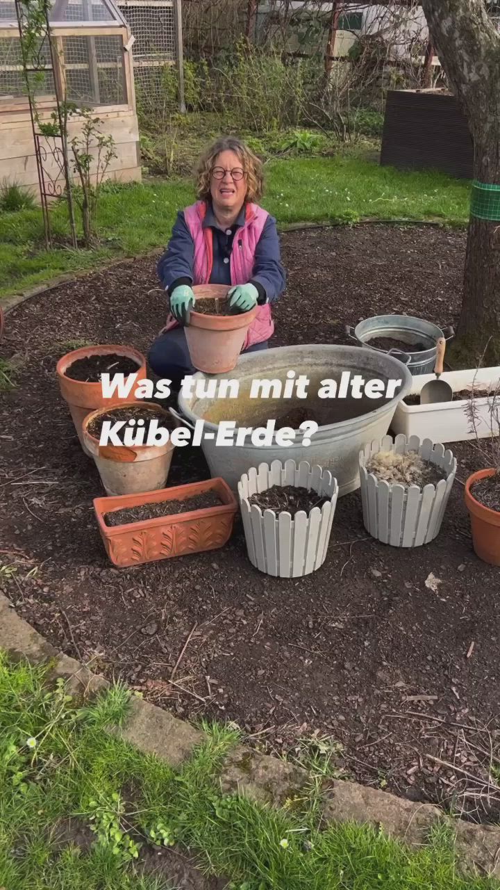 This may contain: a woman sitting in the middle of a garden filled with potted plants and mulch