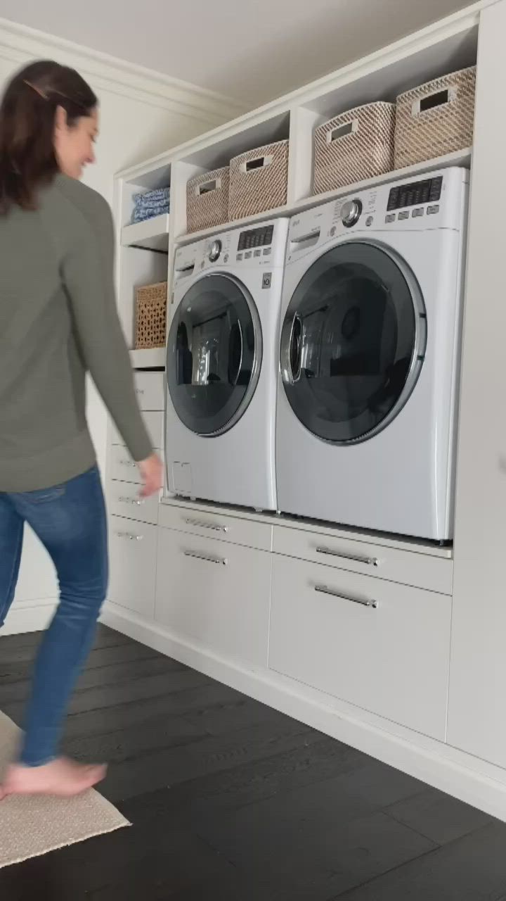 This contains: woman pulling out laundry room shelf under washer and dryer storage shelves