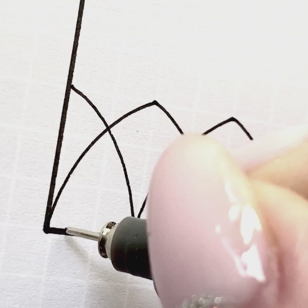 This may contain: someone is using scissors to cut out the outline of a wirework design on a piece of paper