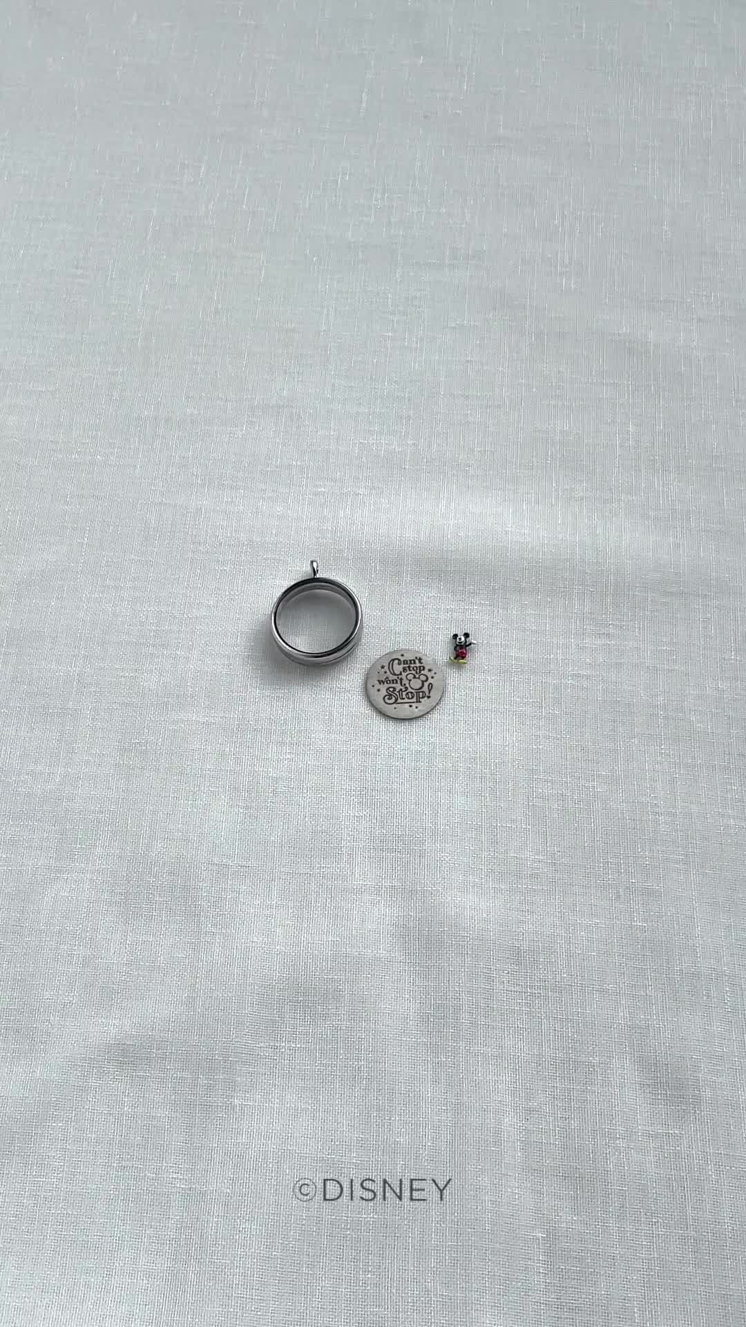 This may contain: a disney pin sitting on top of a white table cloth next to a silver ring