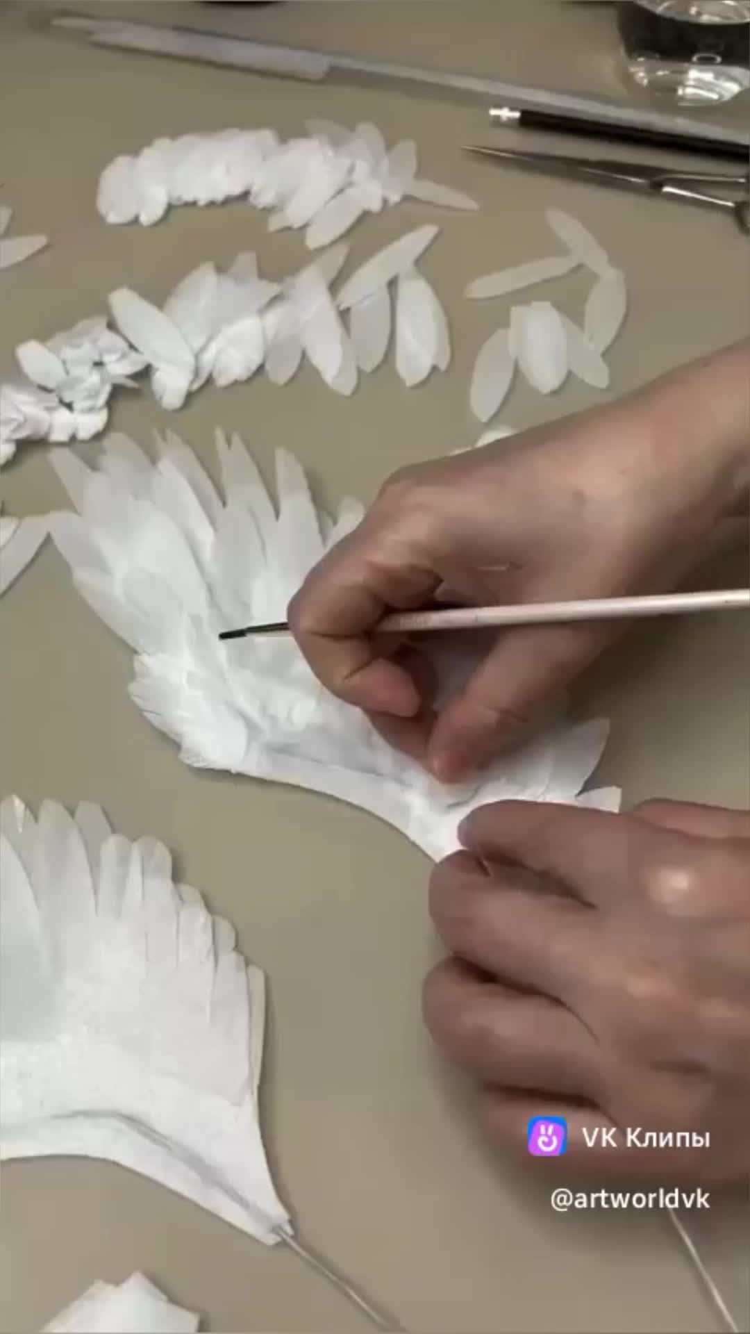 This may contain: someone is making white paper flowers with scissors