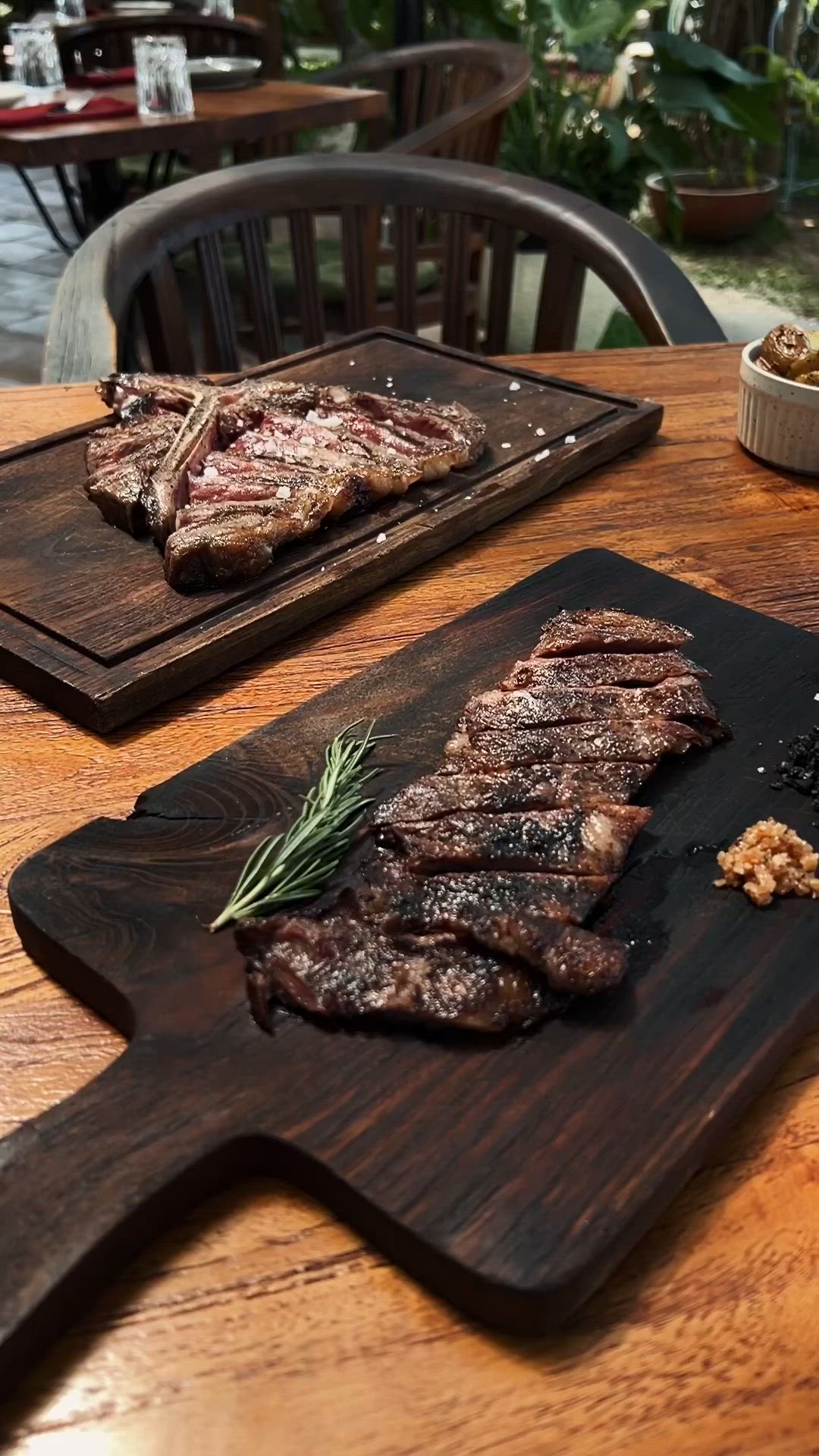 This may contain: some steaks sitting on top of a wooden cutting board