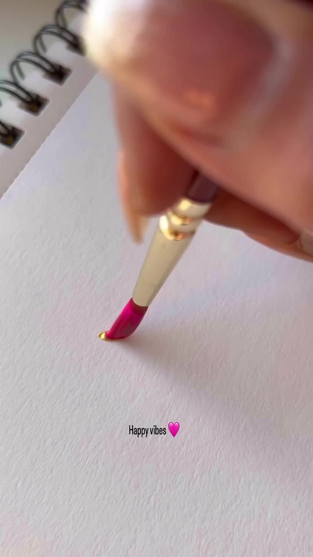 This may contain: a person holding a pen and writing on a piece of paper with a pink flower