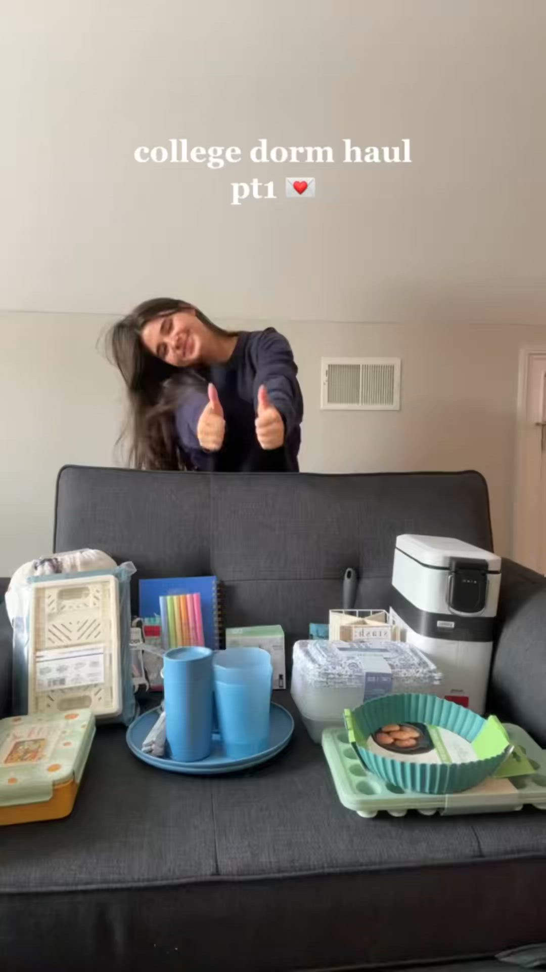 This may contain: a woman giving the thumbs up while sitting on a couch with other items around her