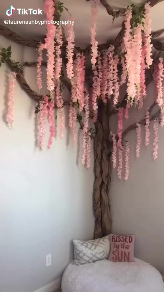 This may contain: a tree with pink flowers hanging from it's branches in the corner of a room