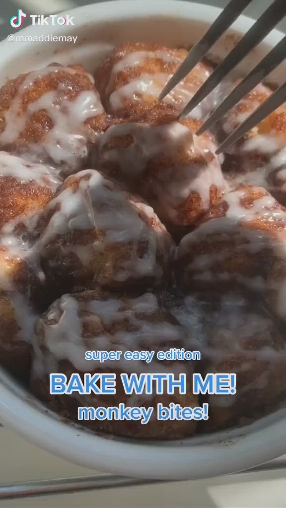 This may contain: a close up of a bowl of doughnuts with icing on top and the words bake with me monkey bread