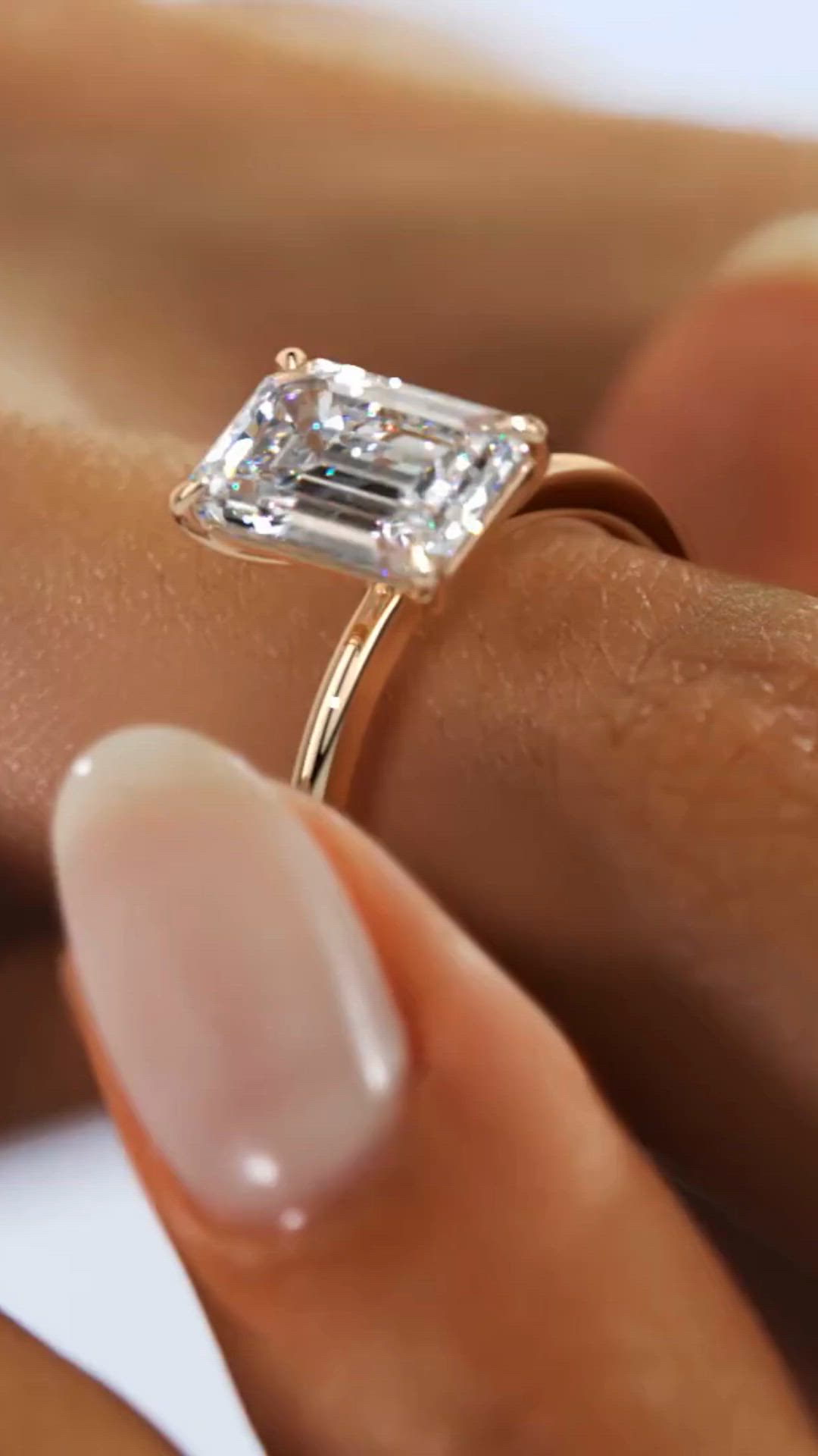 This may contain: a woman's hand holding a diamond ring on top of her finger with the other hand