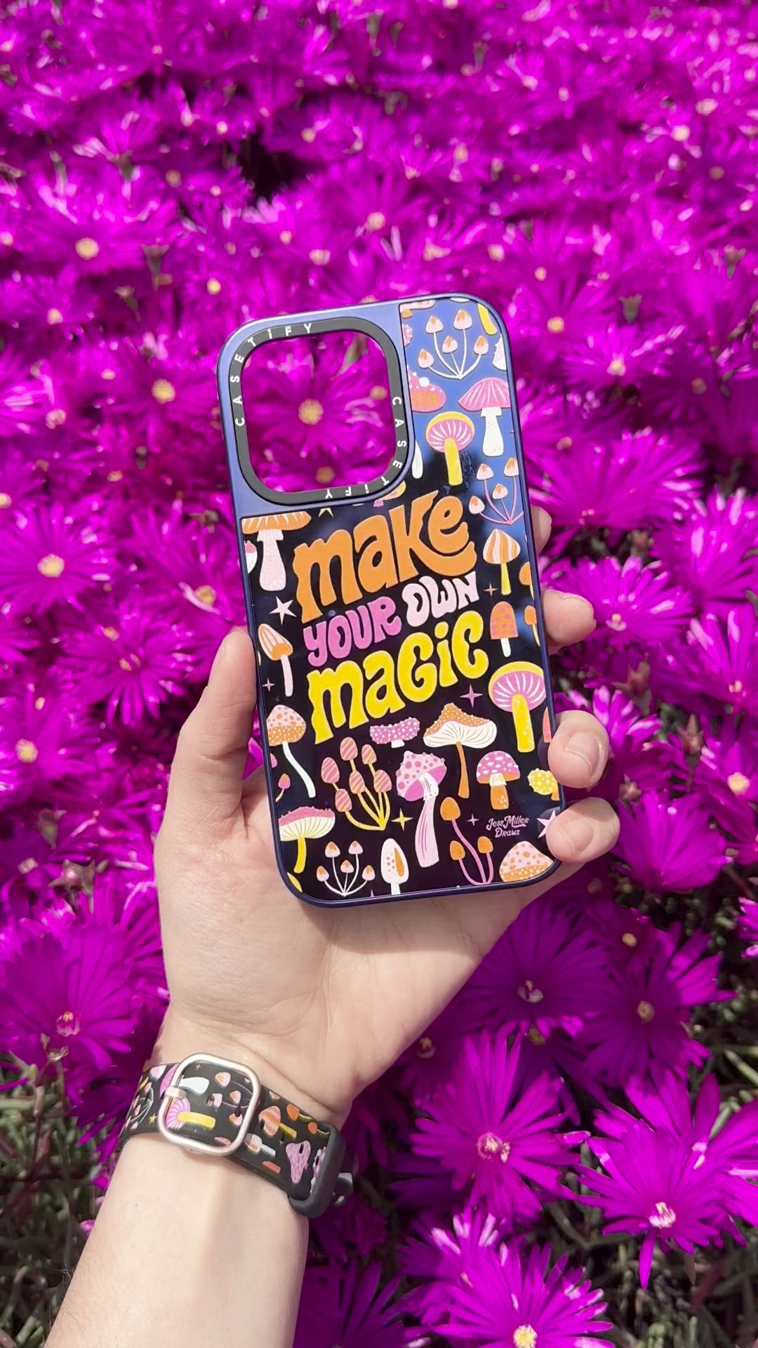 This may contain: a person holding up a phone case with the words make today magic on it in front of purple flowers