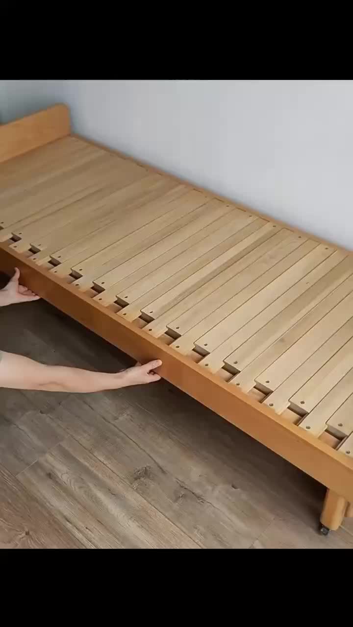 This may contain: a man kneeling down to pick up a mattress from the floor in front of a bookcase