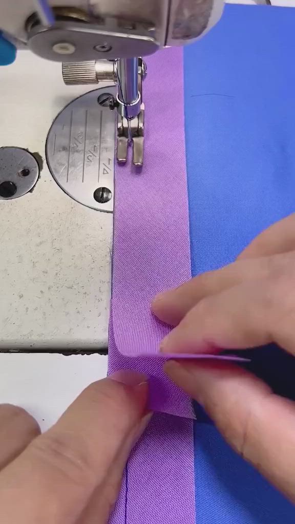 This may contain: someone is using a sewing machine to sew something purple and blue with their hands