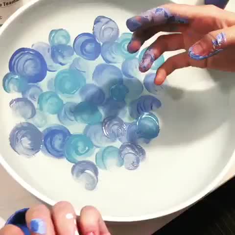 This may contain: two hands reaching for blue and white plastic bottles in a bowl with water on it