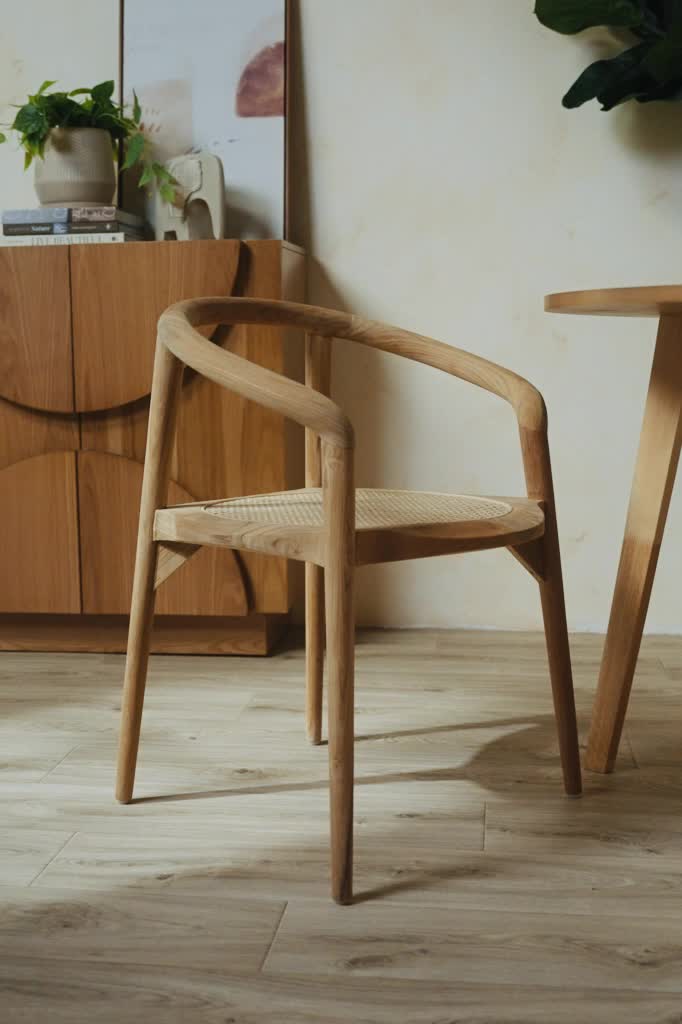 Create an organic feel to your space with this natural teakwood chair featuring modern curved arms and round cane seating. Place in the dining room for entertaining guests or in the office for an elegant look. Natural teak wood frame Rounded cane seating Use as a dining chair or office chair Indoor use only Handmade from a natural material, variance in appearance and coloring may occur Fully assembled