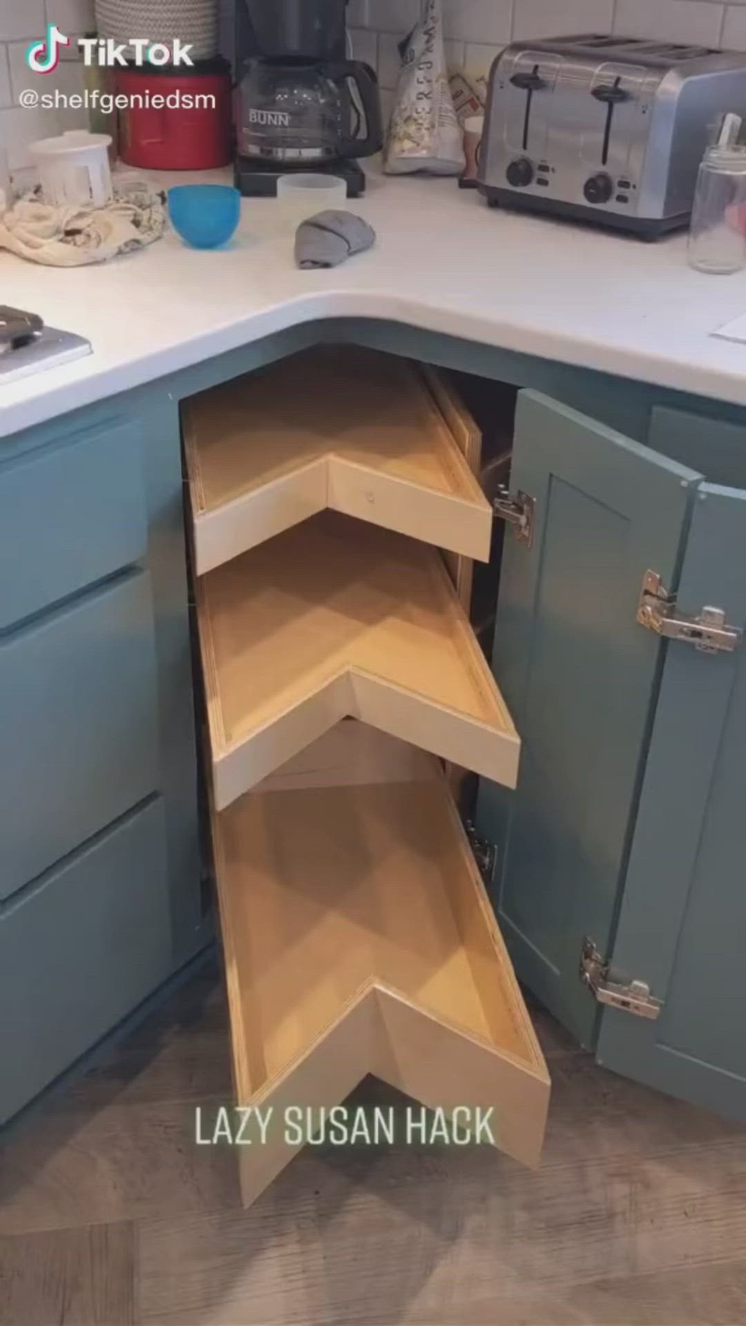 This may contain: a kitchen with blue cabinets and an open corner shelf in the middle that has drawers on both sides