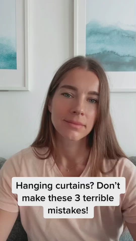 This may contain: a woman sitting on top of a couch in front of two pictures with the caption hanging curtains? don't make these 3 terrible mistakes