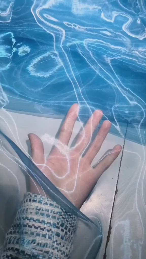 This may contain: a person's hand resting on the edge of a swimming pool with blue water