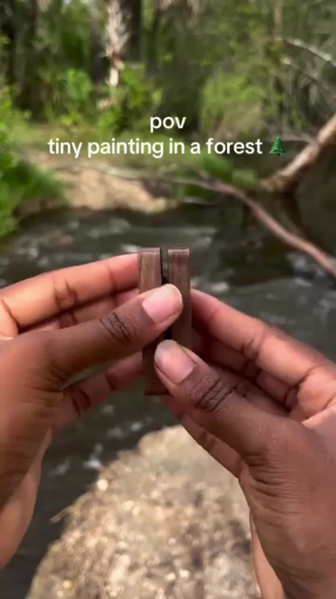 This may contain: a person holding a piece of paper with a small device attached to it, in front of a river