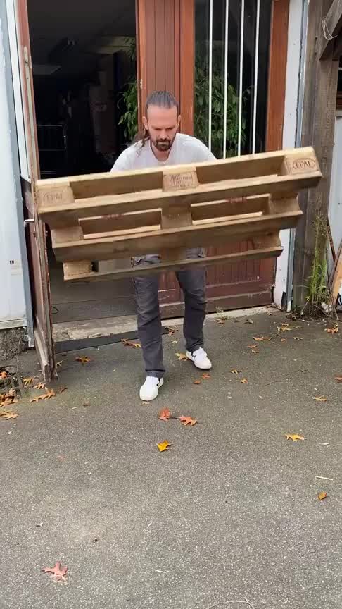 This may contain: a man is holding up a wooden bench in front of a door with bars on it