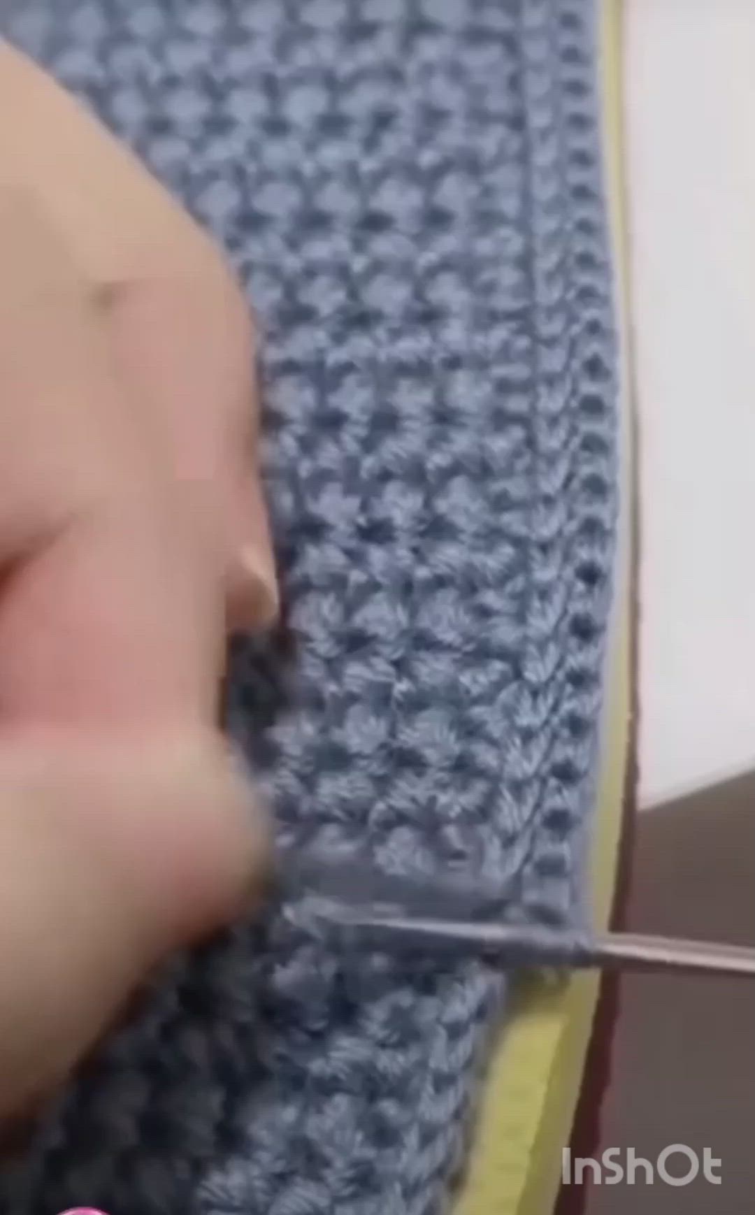 This may contain: someone is crocheting something on a blue blanket