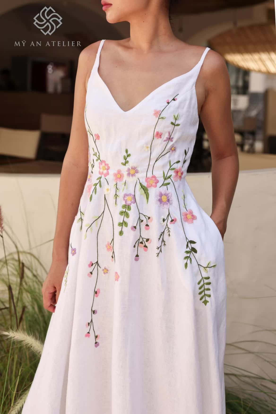 This may contain: a woman wearing a white dress with flowers on it