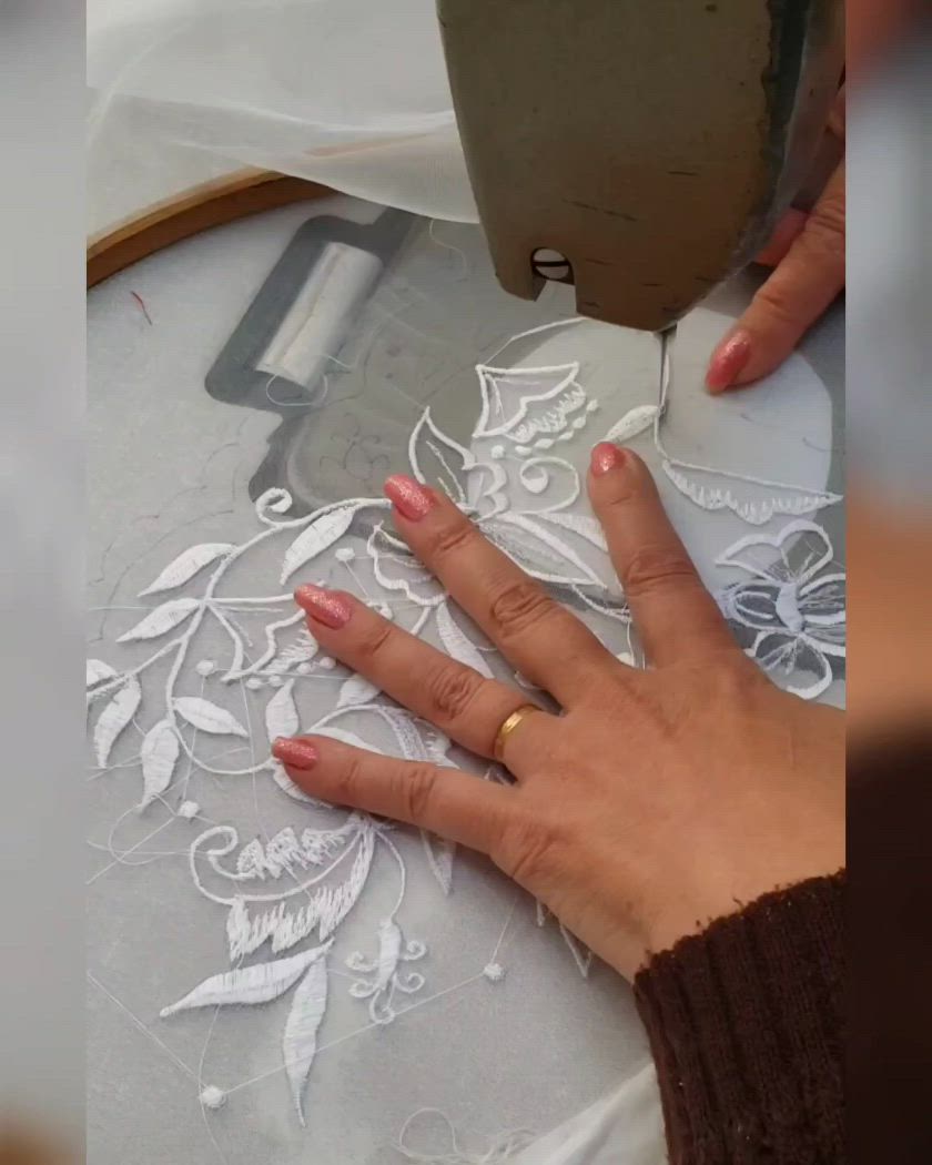 This may contain: a woman is using a machine to embroine the lace on a table cloth