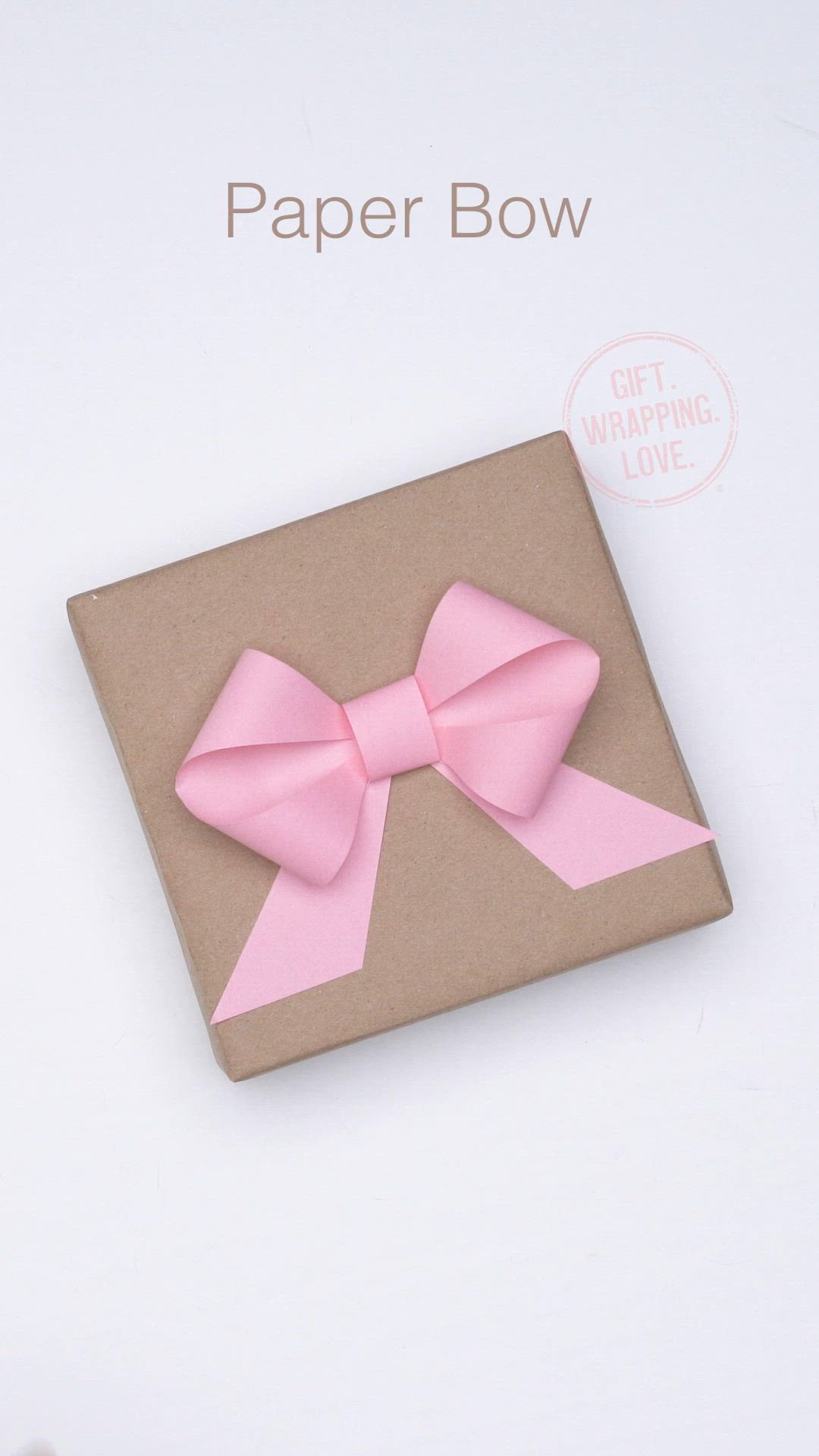 This may contain: a pink bow on top of a brown box with the words paper bow written below it