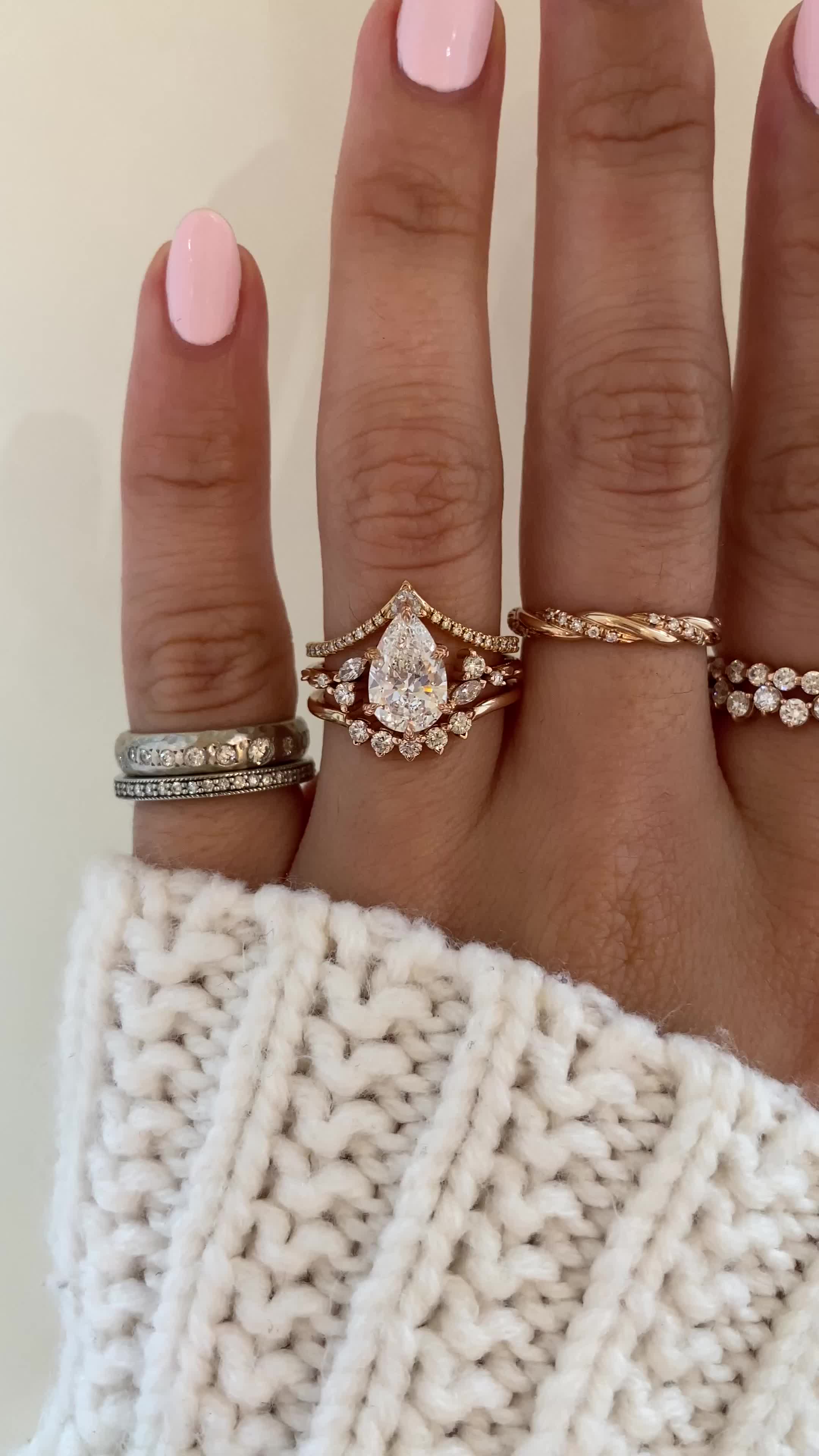 This may contain: a woman's hand with three different rings on her fingers and one is wearing a sweater