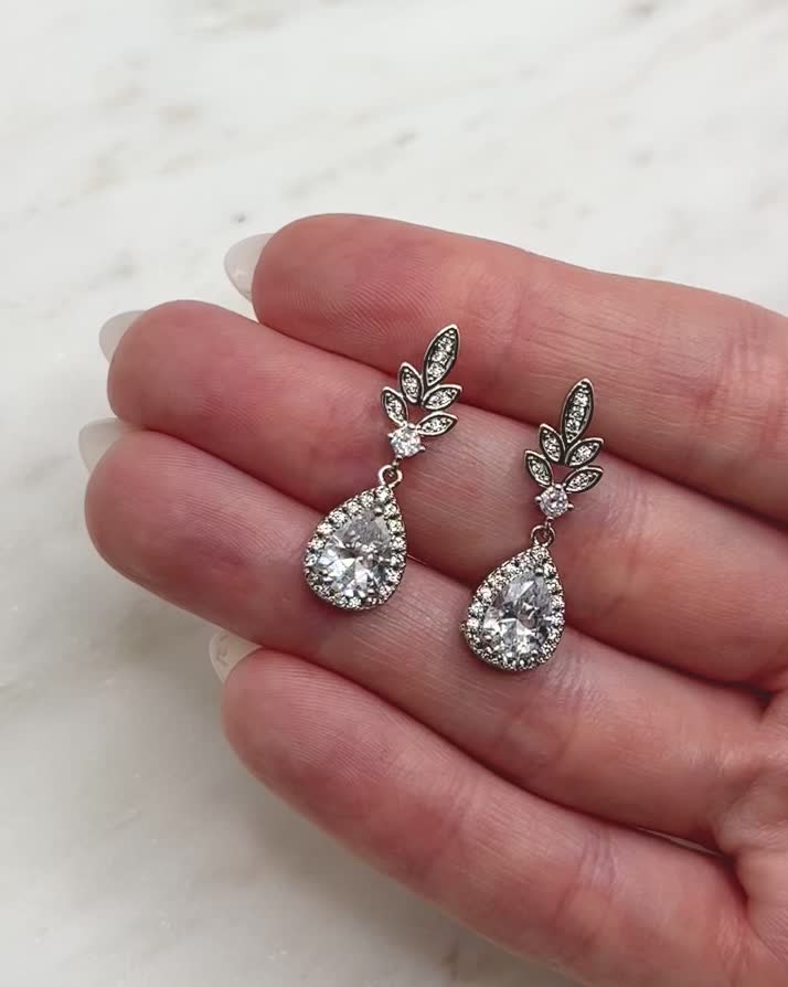 Inspired by the simple beauty of nature, our Emilia Floral CZ Earrings are made with cubic zirconia stones in a delicate, floral design cascading to a shimmering CZ drop. Cubic Zirconia 1" length Hypoallergenic, lead-free & nickel-free Style #4212