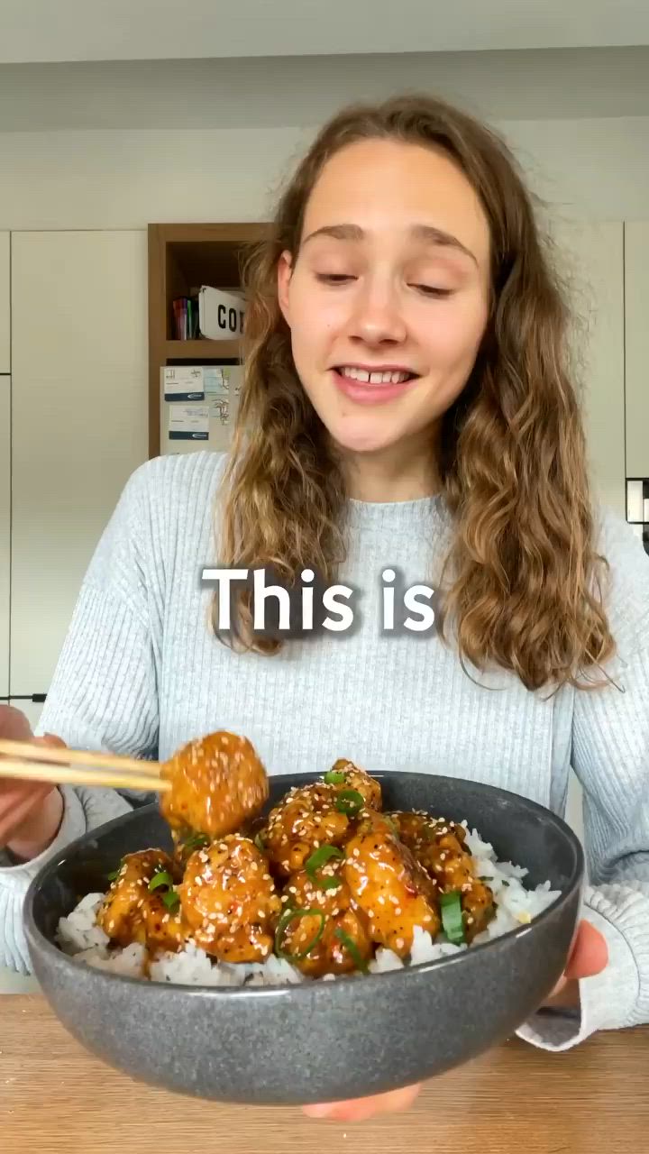 This may contain: a woman holding a bowl full of food with chopsticks in it and the caption reads, this is