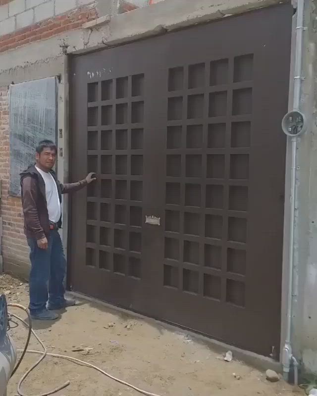 This may contain: a man standing in front of a garage door with his hand on the side of the door