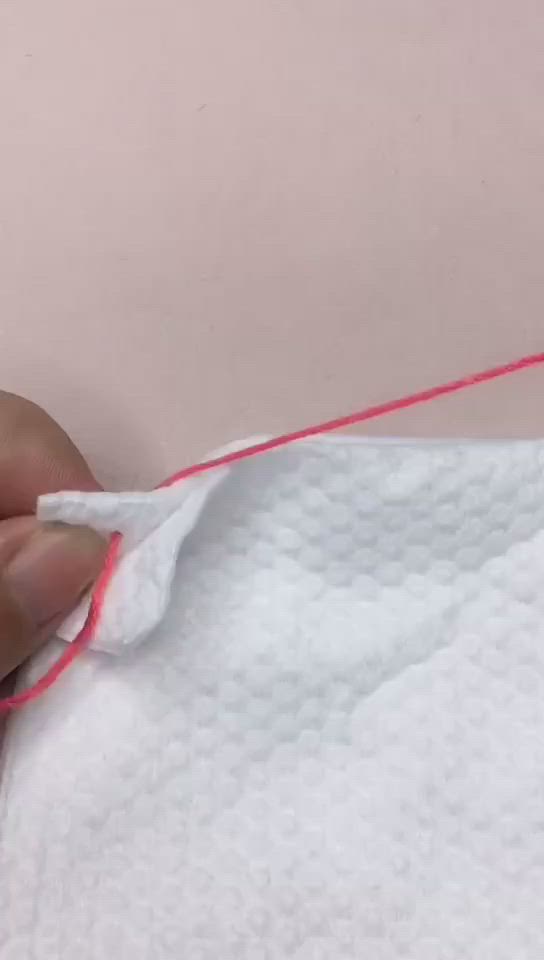 This may contain: someone is sewing something on a piece of white fabric with red thread in the middle