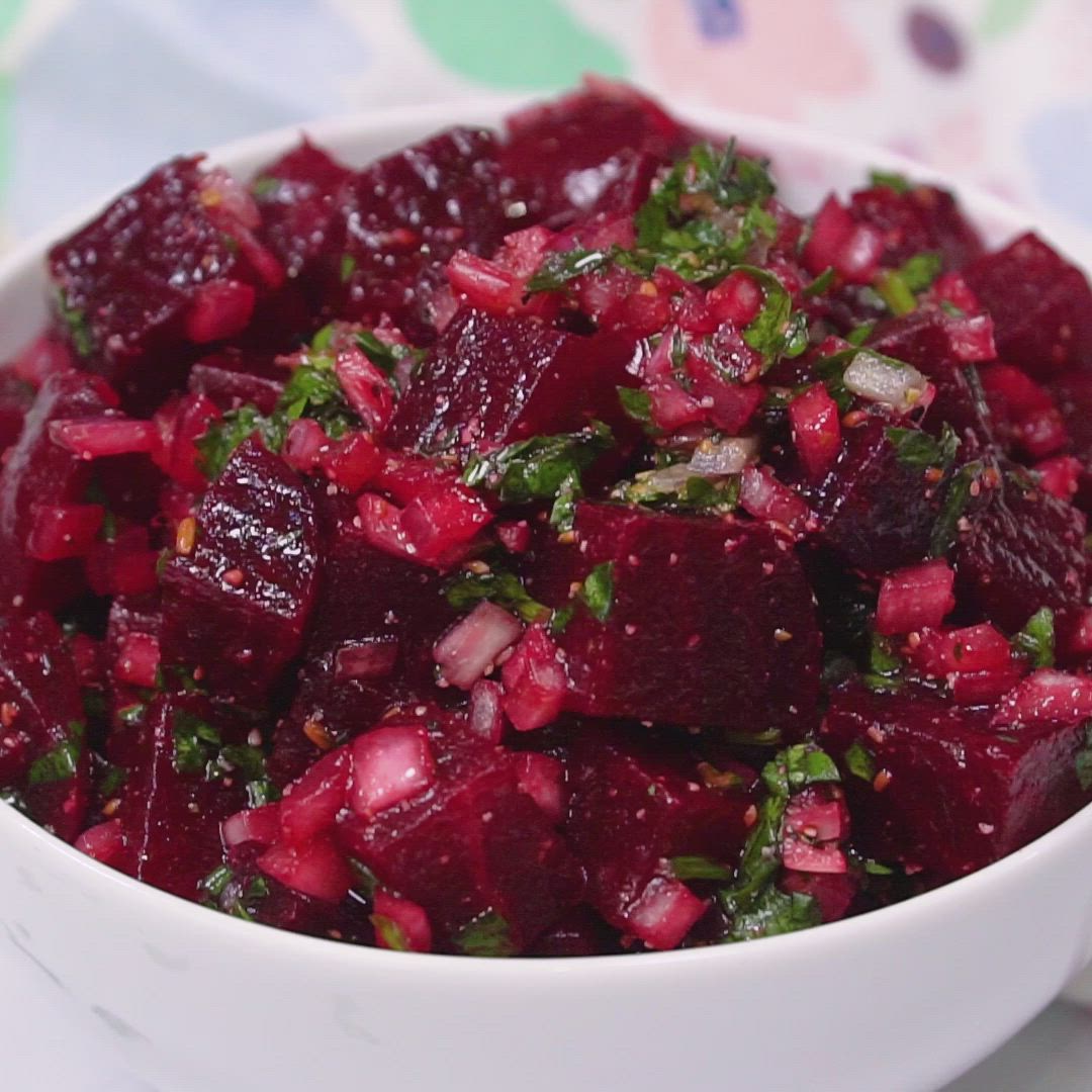 This may contain: a white bowl filled with beets on top of a table