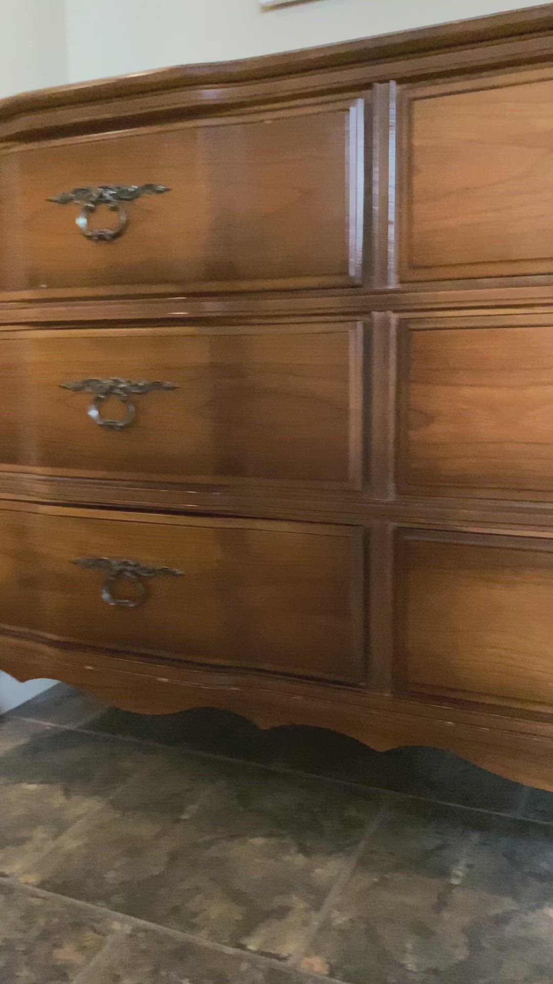 This may contain: a large wooden dresser sitting on top of a tiled floor