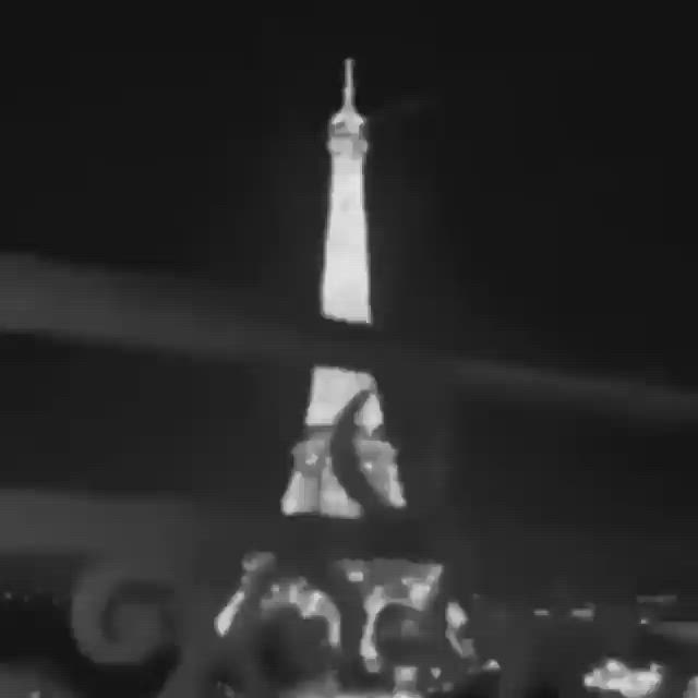 This may contain: the eiffel tower is lit up at night