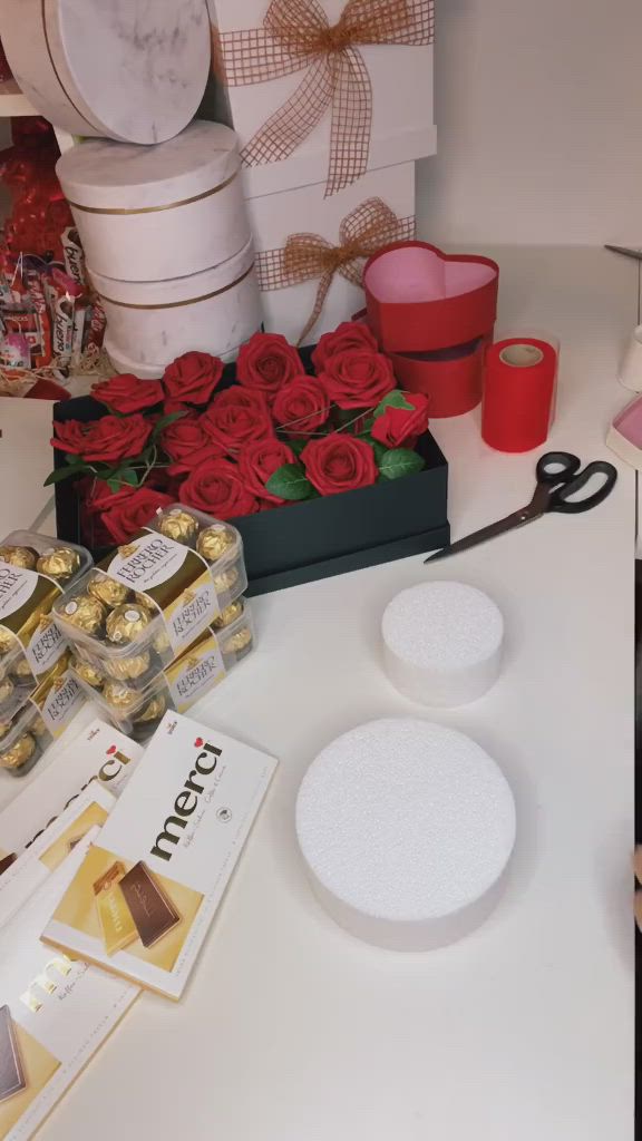 This may contain: a person holding a bowl filled with gold and red flowers on top of a table