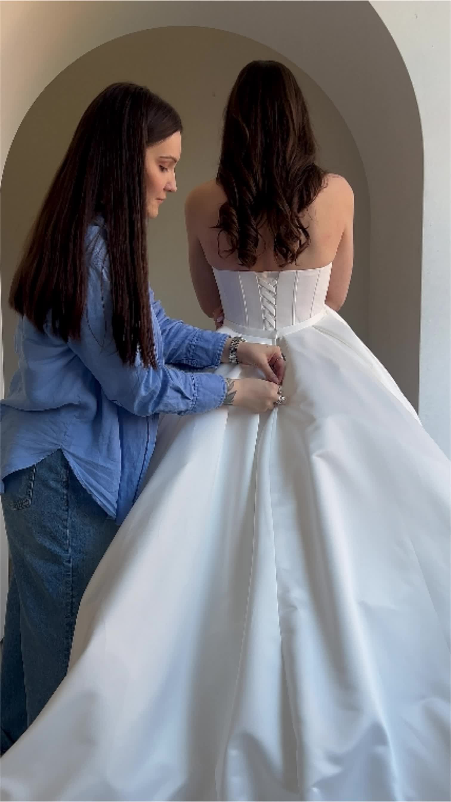 This may contain: two women in wedding gowns looking at each other