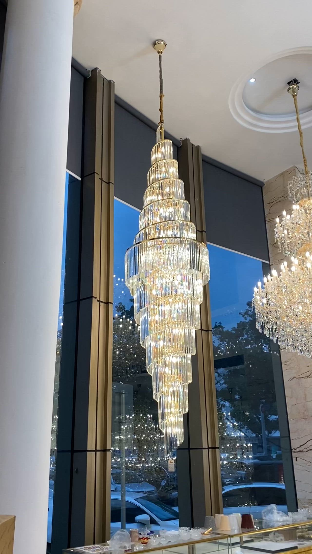 This may contain: a large chandelier hanging from the ceiling in a room with tall columns and windows