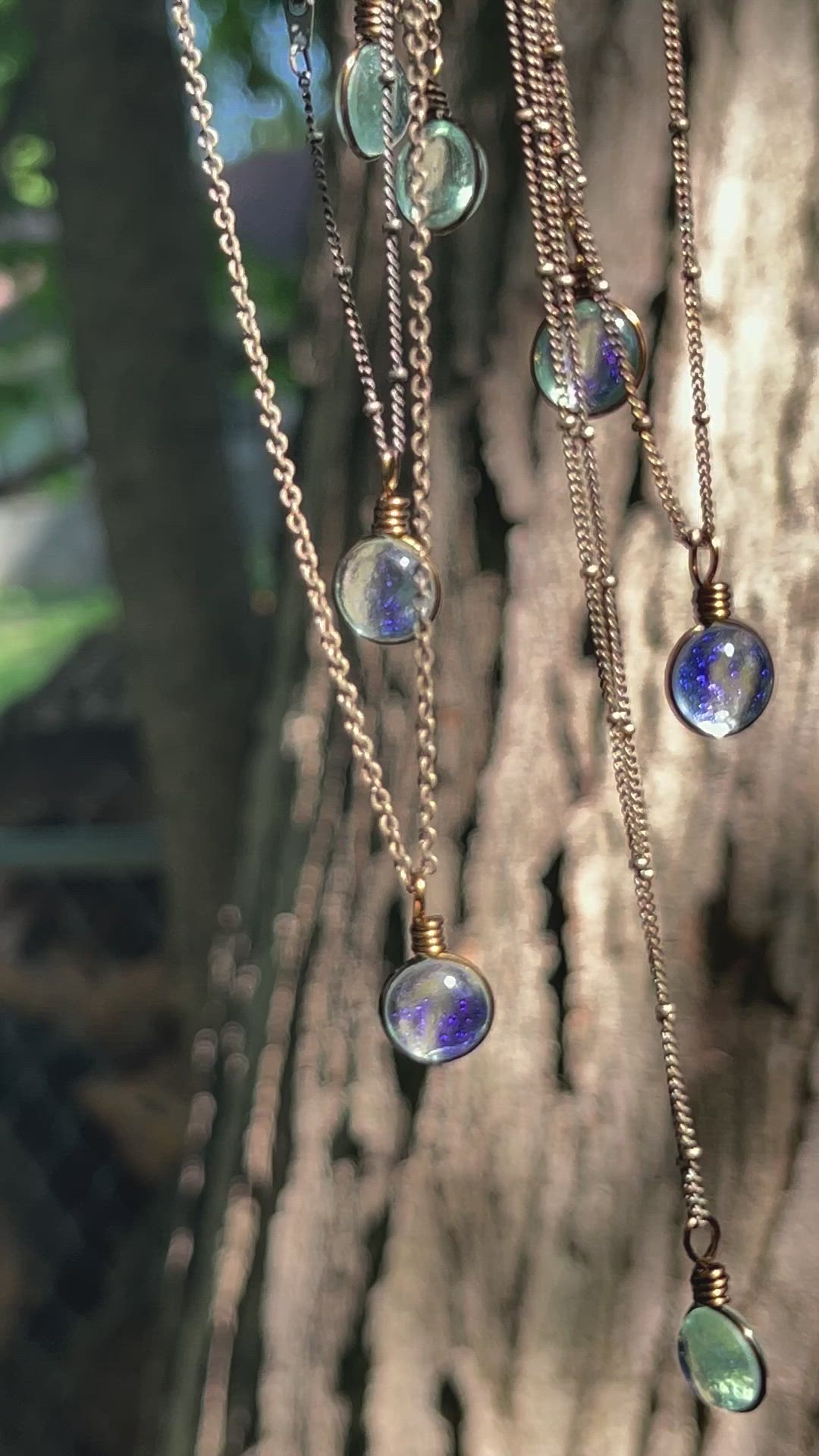 This contains: The transparent green tinted glass used in this minimalist necklace is the perfect cool sage green for a single drop of rain.
The sparkle is subtle and changes depending on the lighting and background. Our simple brass style chain gives an earthy vintage aesthetic.