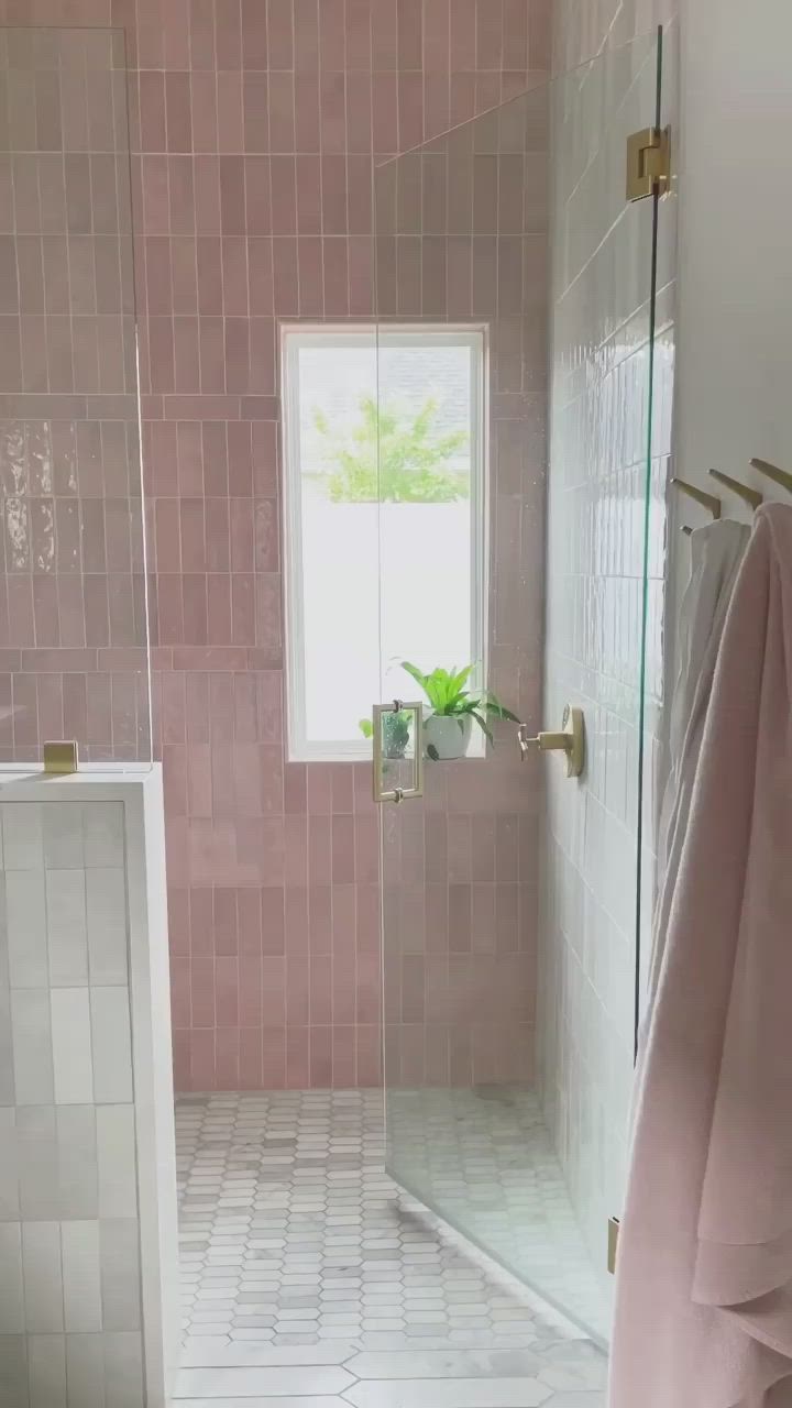 This may contain: a shower head and hand shower in a pink tiled bathroom with gold faucet