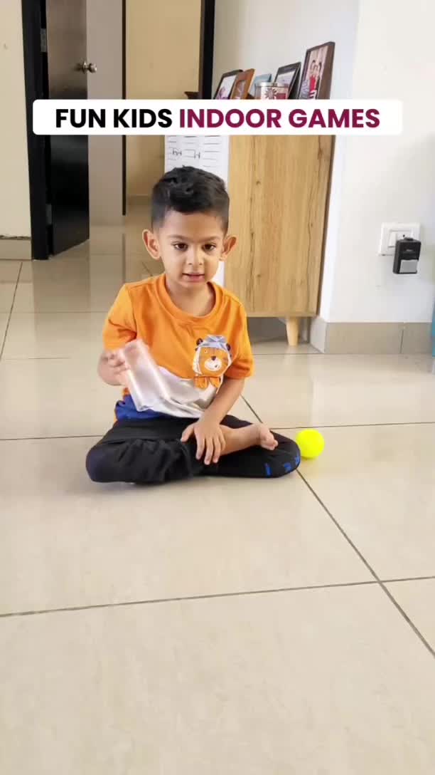 This may contain: a young boy sitting on the floor with a tennis racket