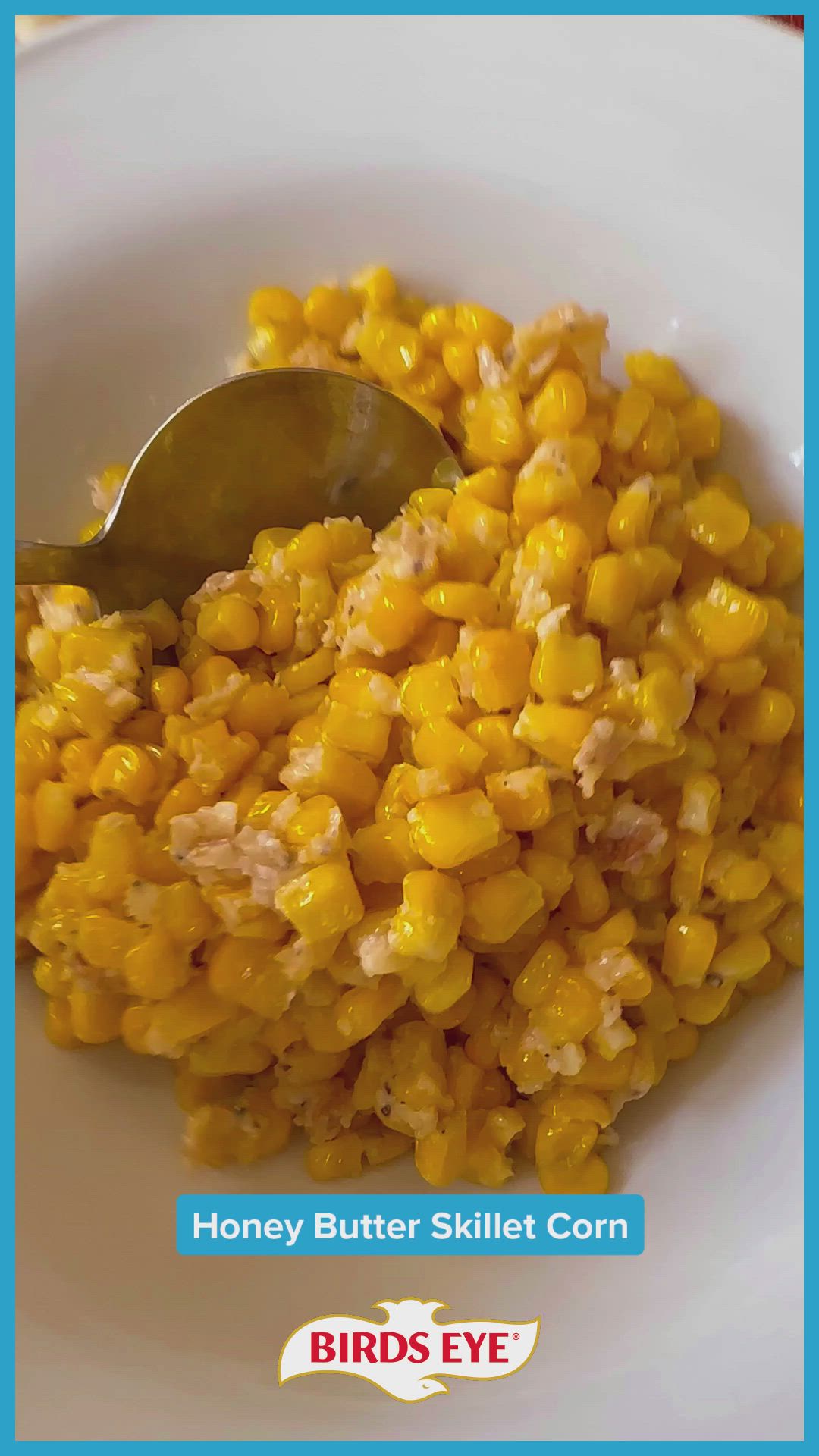 This may contain: a white bowl filled with corn next to a spoon and blue border around the bowl