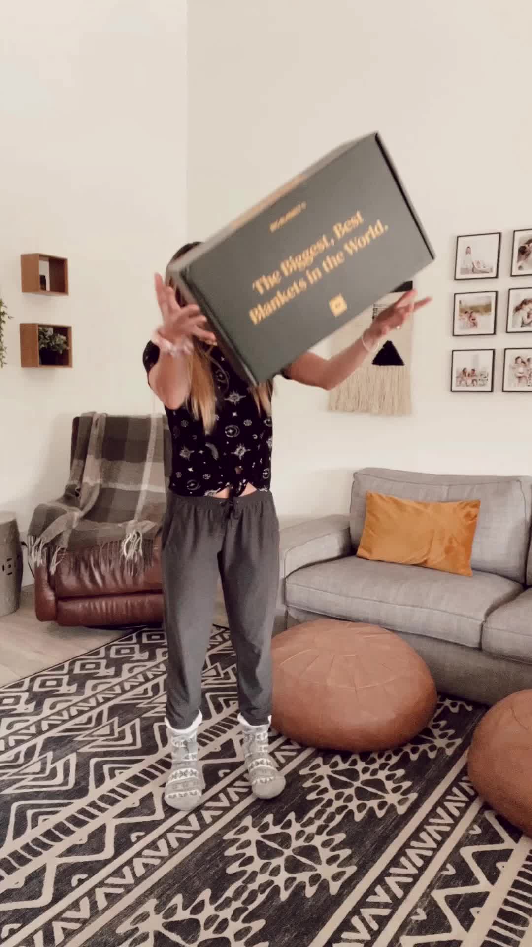 This may contain: a woman standing in a living room holding up a large box