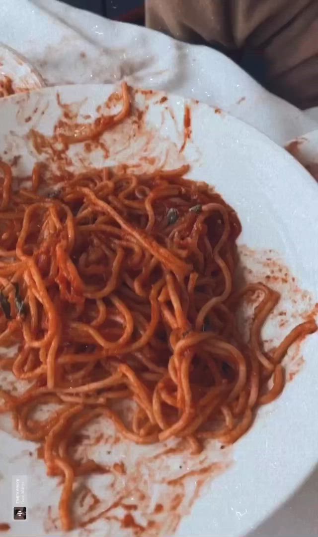 This may contain: a white plate topped with spaghetti and sauce