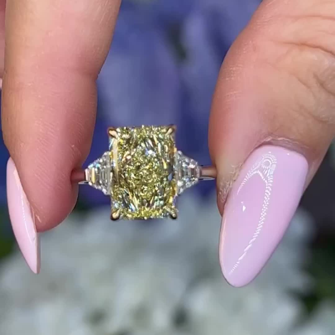 This may contain: a close up of a person's hand with a ring on their finger and a yellow diamond in the middle