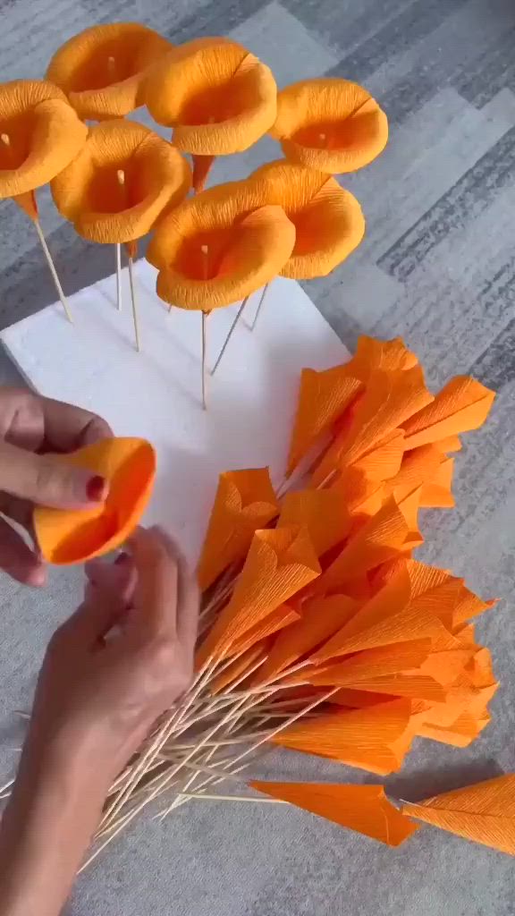 This may contain: someone is decorating orange flowers with sticks