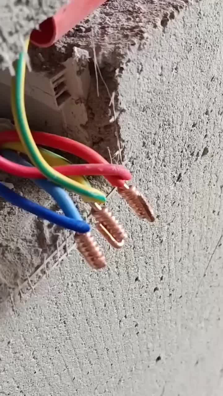 This may contain: several wires are connected to an electrical outlet in a concrete wall with a water bottle